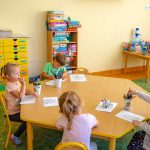 Dzieci siedzą przy stole i rysują