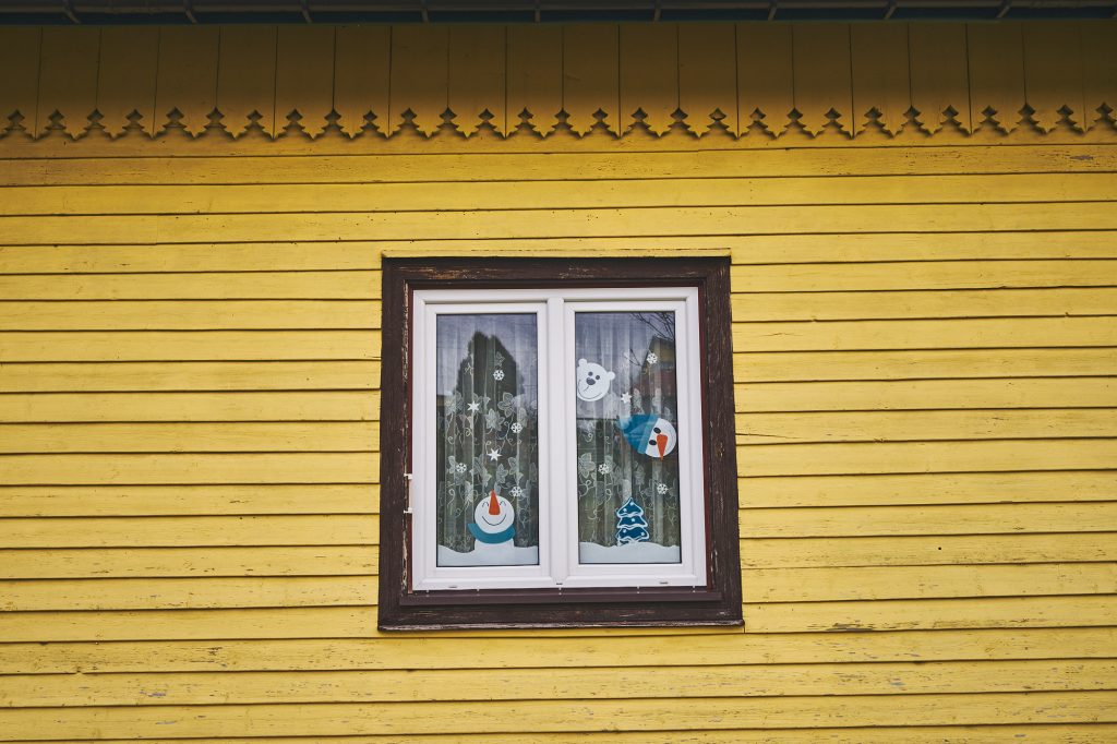 Okno w drewnianym budynku w kolorze żótym