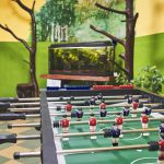 Na korytarzu szkolnym stoi sół do gry piłkarzyki. W głebi szklane akwarium