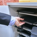 Ręka mężczyzny wyciaga laptopa z szafy