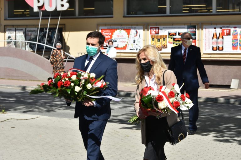 Młody mężczyzna i kobieta składają kwiaty pod pomnikiem