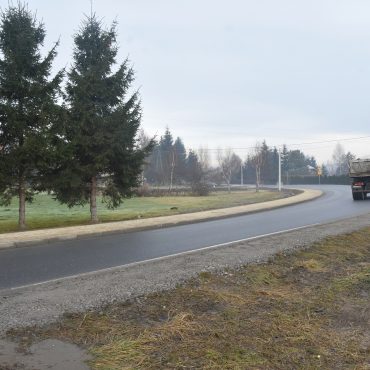 Widok na drogę główną przy której znajduje się nowo wybudowany chodnik oraz po której przejeżdża ciężarówka.