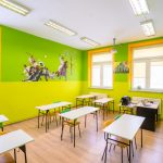 Odświeżone ściany na kolor zielony w klasie w szkole. Wewnątrz znajdują się stoliki i krzesła.