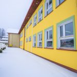 Odmalowana na żółto elewacja budynku szkoły. Zdjęcie robione w zimowej odsłonie.