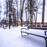 Drewniana ławka w parku przykryta śniegiem