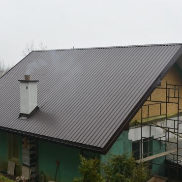 Budynek murowany z nowym dachem z brązowej blachy.