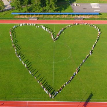 Zdjęcie z drona, płyta stadionu, boisko lekkoatletyczne, na środku serce z ludzi.