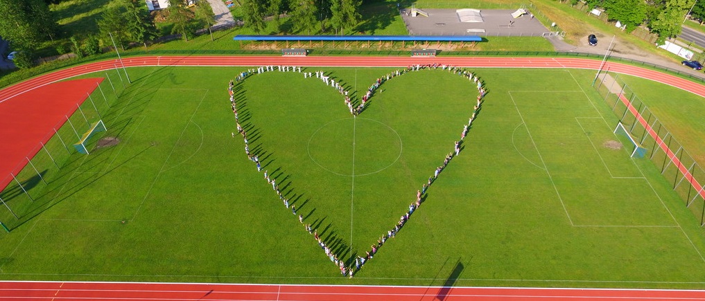 Zdjęcie z drona, płyta stadionu, boisko lekkoatletyczne, na środku serce z ludzi.