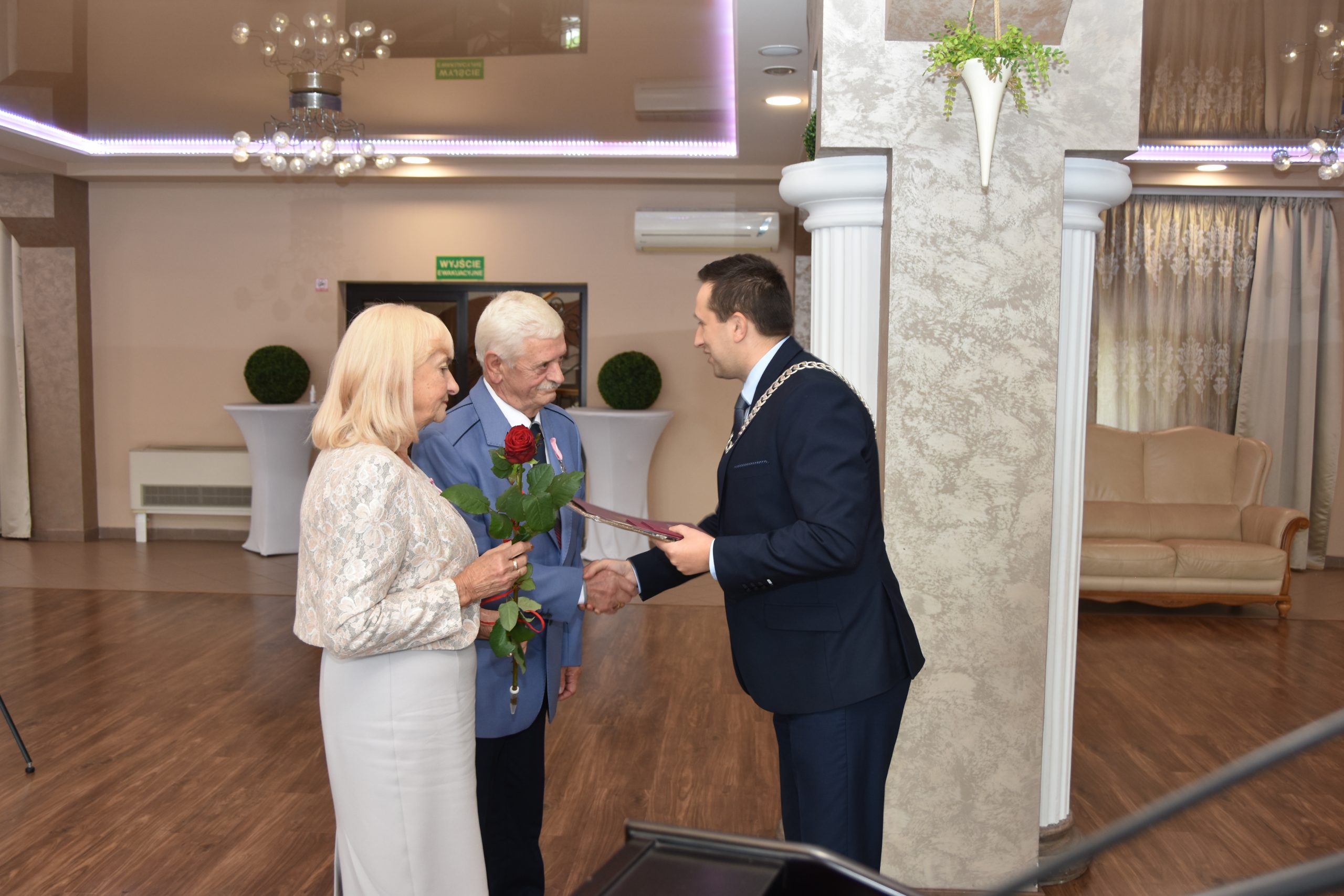 Burmistrz Brzozowa Szymon Stapiński wręcza medale i listy gratulacyjne parze z pięćdziesięcio letnim stażem małżeńskim, gratulując i uściskując dłonie