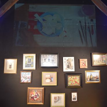 Grupa kilkunatu obrazów średniej wielkości powieszonych na ścianie.