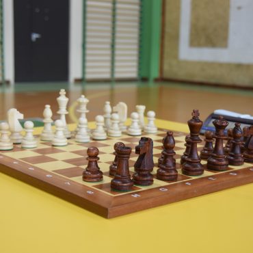 Szachownica z ułożonymi do gry szachami leząca na stole.