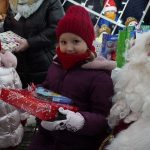 Grupa dzieci otrzymujących prezenty od św. Mikołaja.