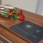 Ozdobne okładki z napisem Burmistrz Brzozowa oraz dwie czerwone róże na biurku.