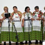 Grupa kobiet w ludowych strojach spiewają kolędę.