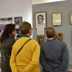 Trzy starsze kobiety obrócone plecami oglądają obrazy zawieszone w muzeum.