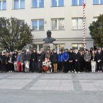 Duża grupa osób głównie młodzieży obojga płci stojaca przy popiersiu Piłsudskiego przed gmachem urzędu.