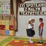 Chłopczyk i dziewczynka podczas wystepu teatralnego. Z tyłu widać napis XVI Spotkanie z Małym Teatrzykiem.
