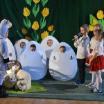 Grupa dzieci przebrana za pisanki i królika w czasie wielkanocnego teatrzyku.