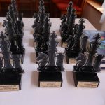 Statuetki i nagrody szachowe zaprezentowane na stole.