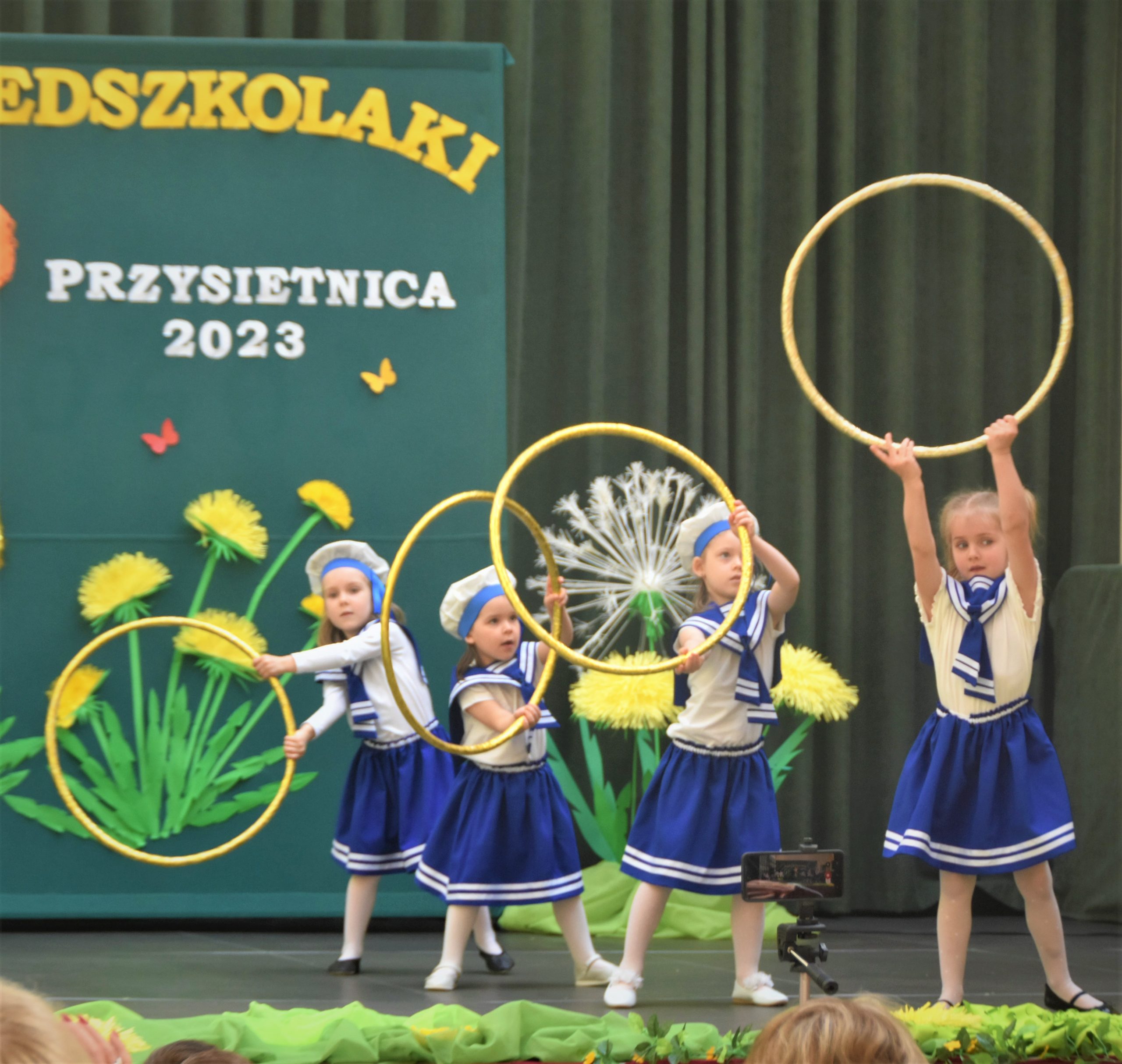Czwórka dziewczynek w wieku przedszkolnym wykonująca układ taneczny.