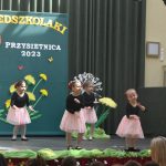 Czwórka dziewczynek w wieku przedszkolnym wykonująca układ taneczny.