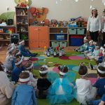 Grupa dzieci bawi się na kolorowym dywanie w przedszkolu.